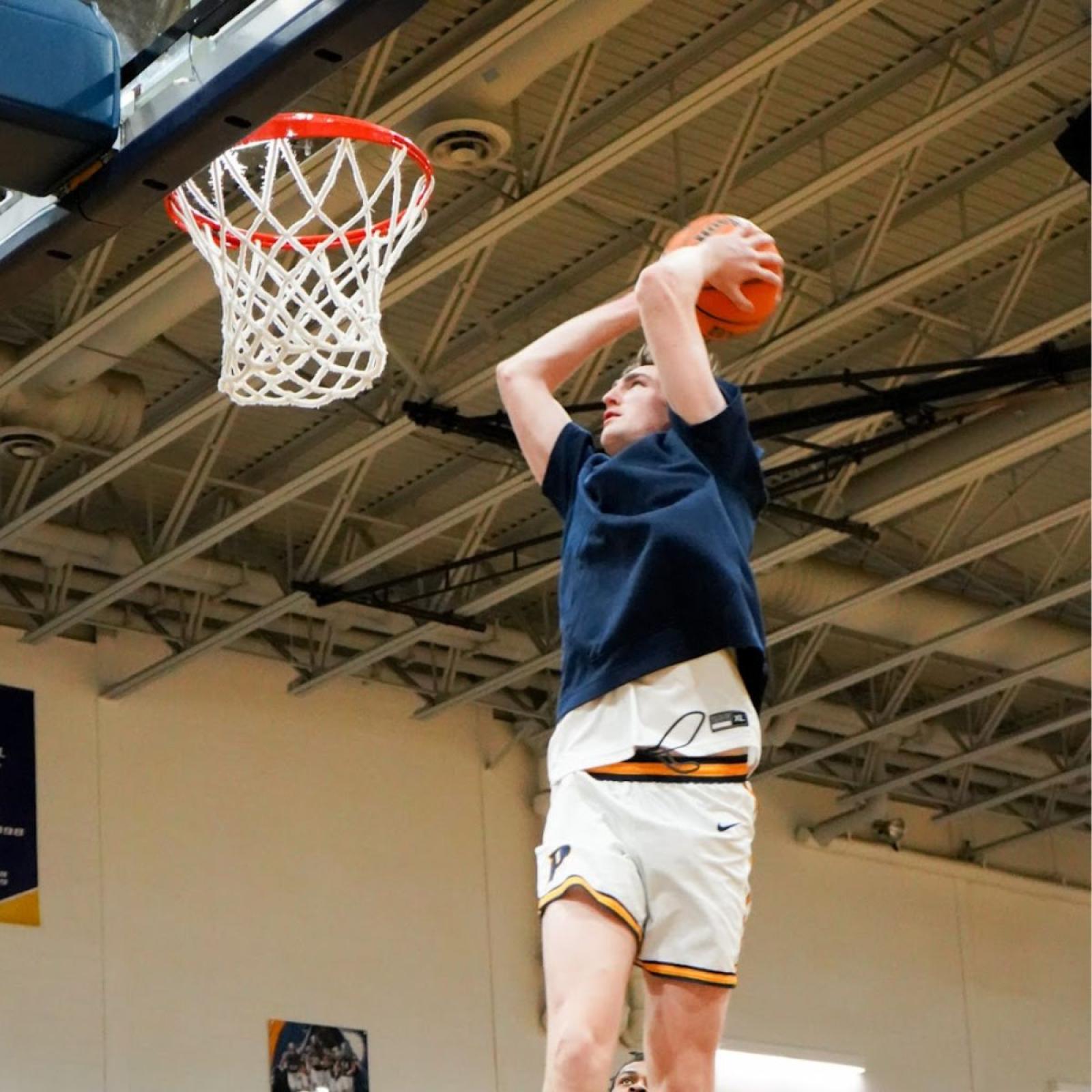 Pace University student Just O'Neill dunking a basketball into the hoop at a game for Pace's Men's Basketball team.