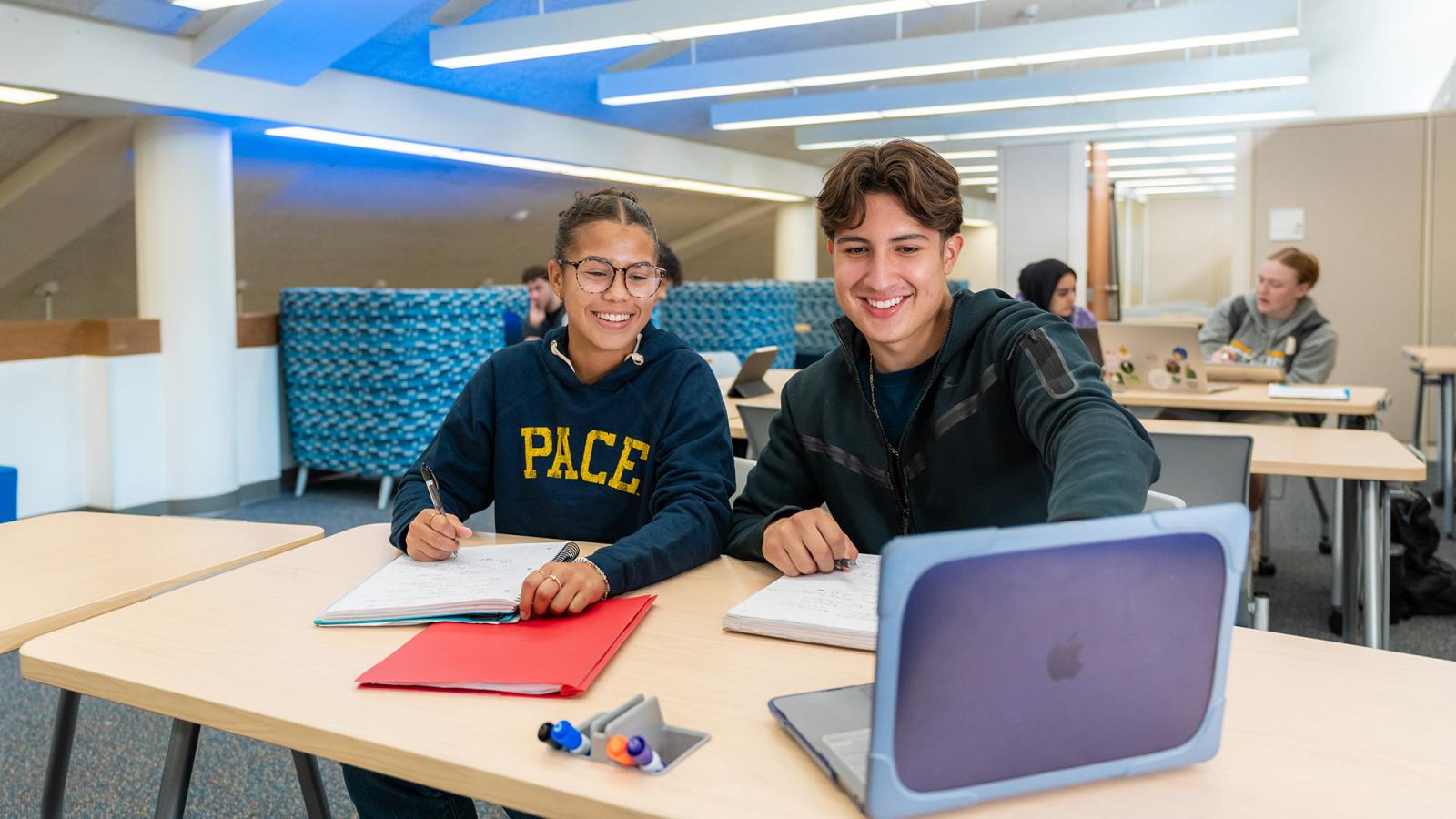 Two Pace students sit in the Learning Commons with a laptop