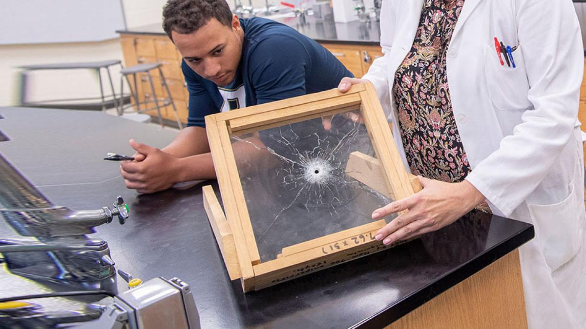 Student with professor analyzing ballistics glass