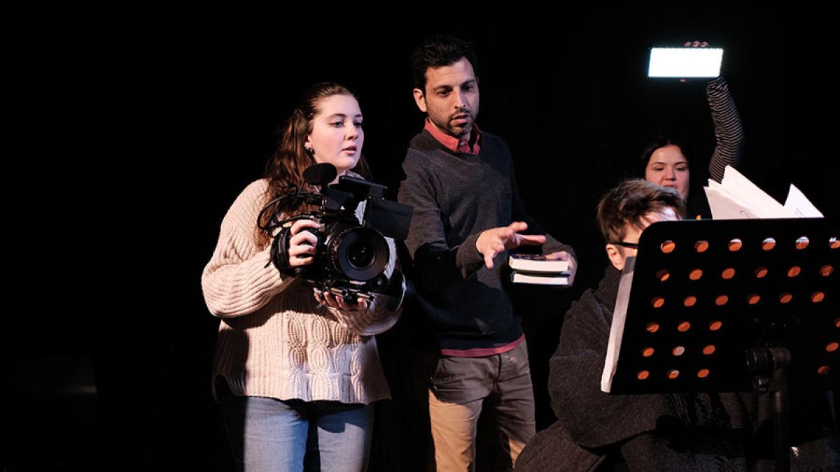 Pace University's Media, Communications, and Visual Arts students filming with one holding a camera, one directing, and one holding a light