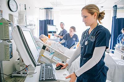 young woman in scrubs at computer at the Pace University Lienhard School of Nursing