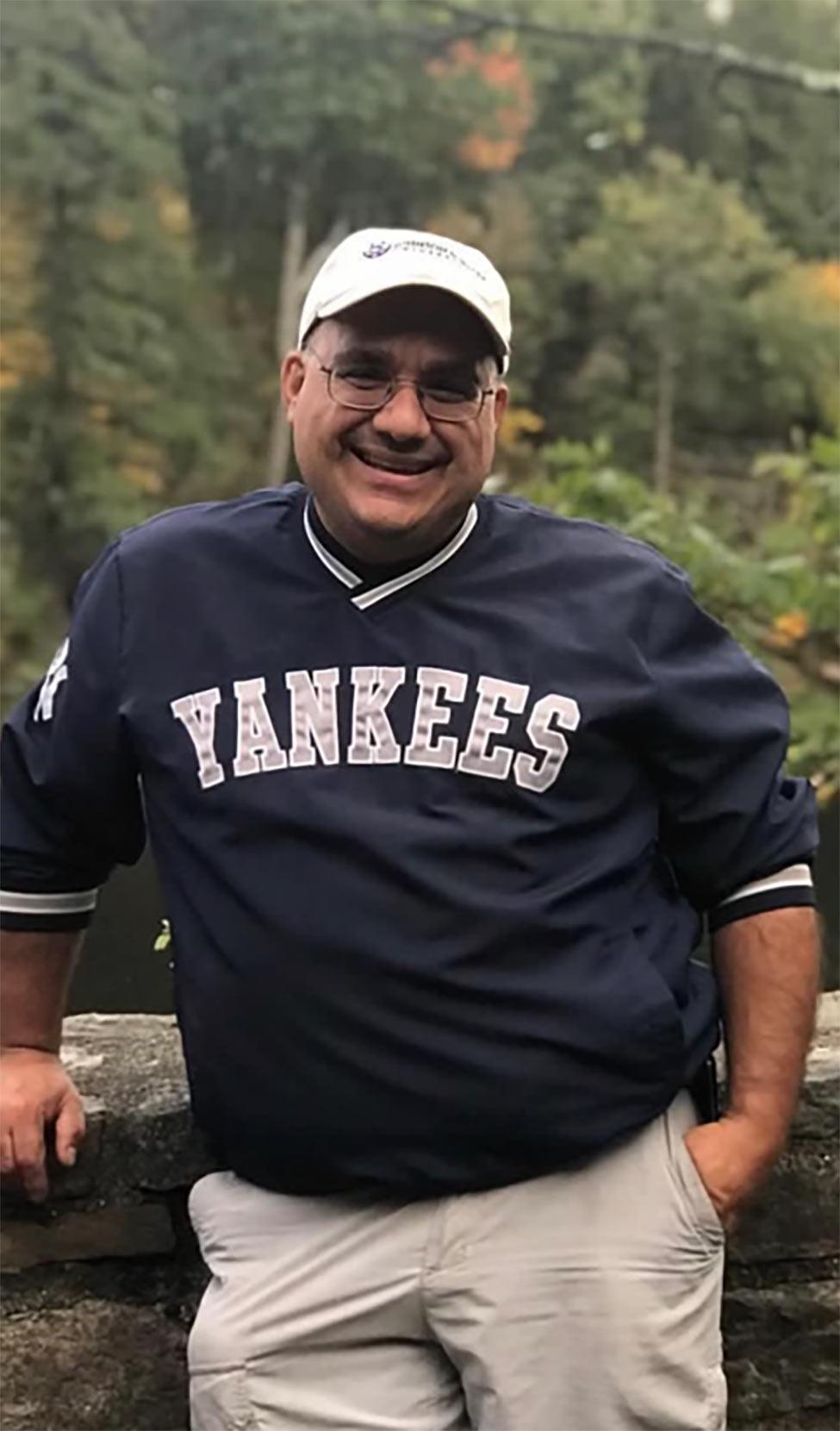 man in baseball cap smiling with trees in background