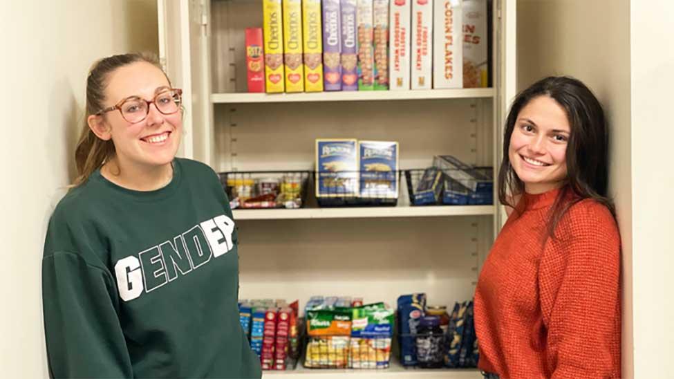 Two Haub Law students show off the campus food pantry