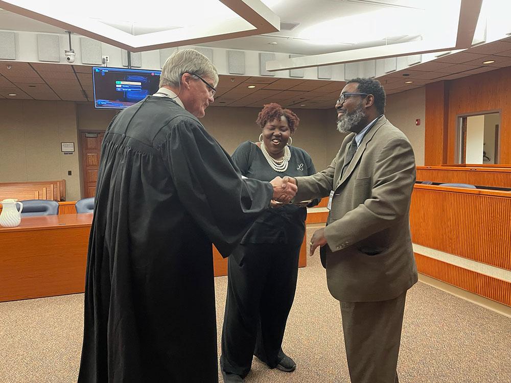 two men shaking hands and a woman smiling