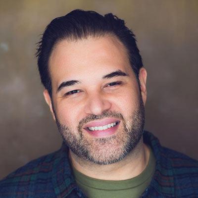 Portrait of Erick Betancourt smiling with brown background