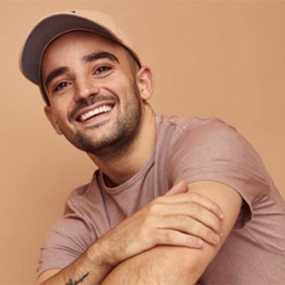 Portrait of Steven Blandino wearing a ball cap with a tan background