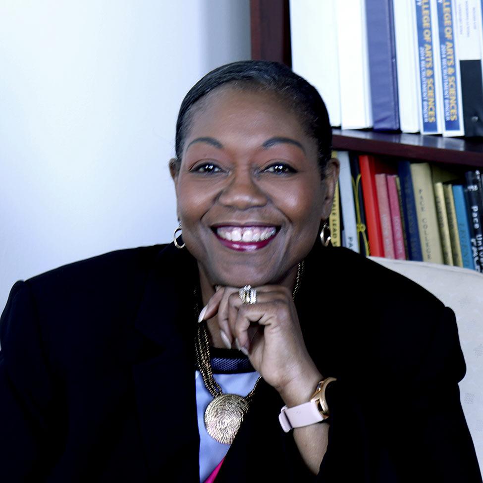 Tresmaine Grimes sitting in a chair with books on a shelf behind her