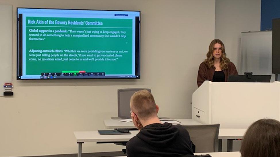 young woman at a podium presenting a powerpoint presentation