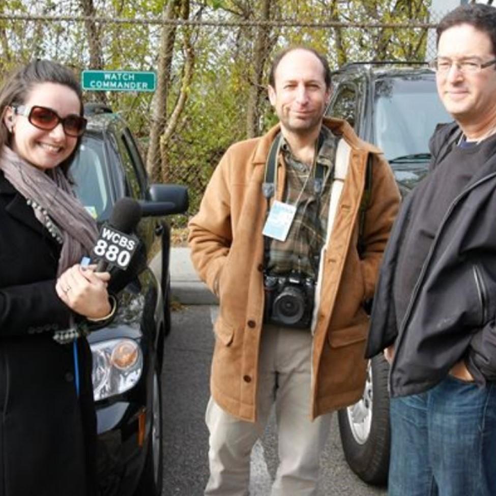 Elisabeth Haub School of Law alumna Catherine Cioffi '12 with microphone in hand, standing with 2 reporters