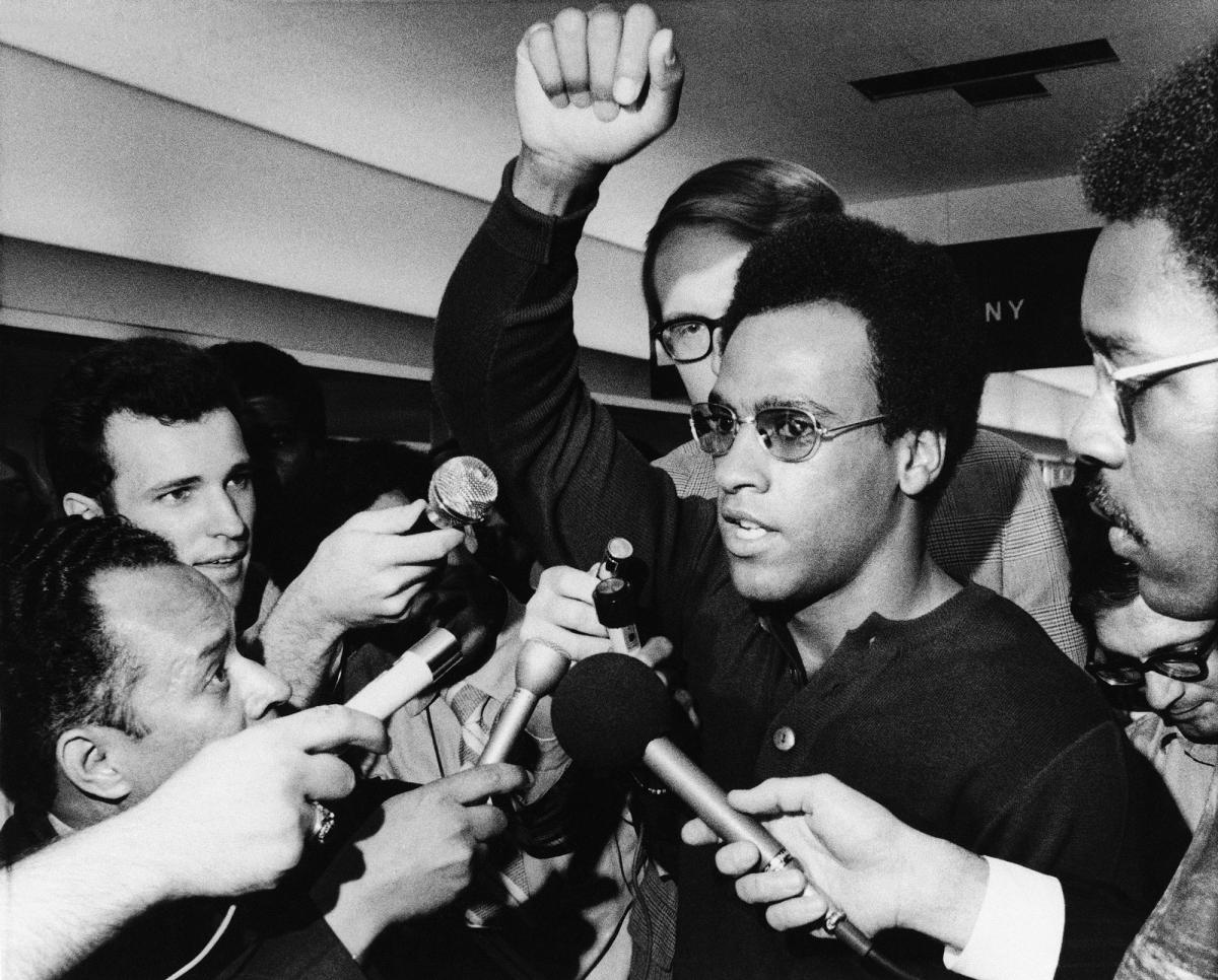 Huey P. Newton, Black Panther party minister of defense, raises his arm as he is literally surrounded by newsmen and others at Philadelphia’s International Airport on Friday, Sept. 4, 1970 in Philadelphia upon his arrival for a three-day convention.