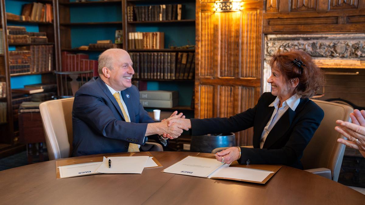 Pace University President Marvin Krislov shaking hands with Gale Epstein at a conference table.