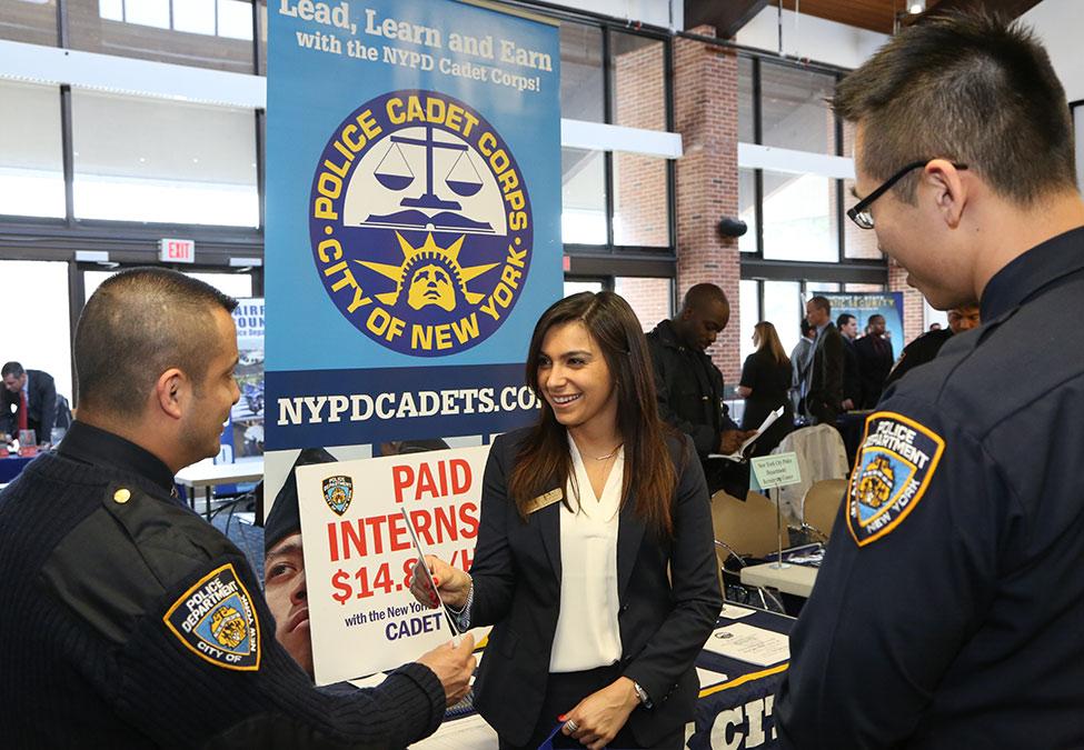 Pace University Criminal Justice career fair with police officers speaking with a female at a table