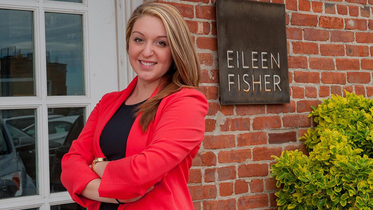 Student standing in front of a sign that reads Eileen Fisher.
