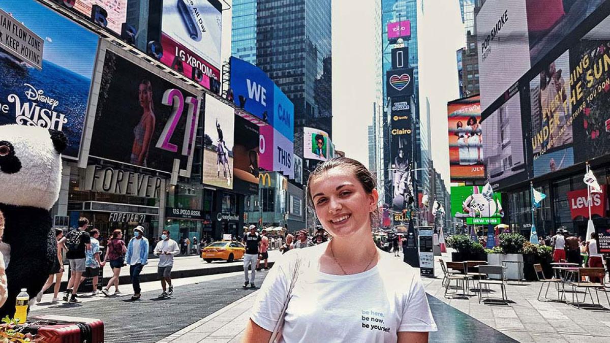 A young woman, Julia Sroczy, stands in the middle on Times Square