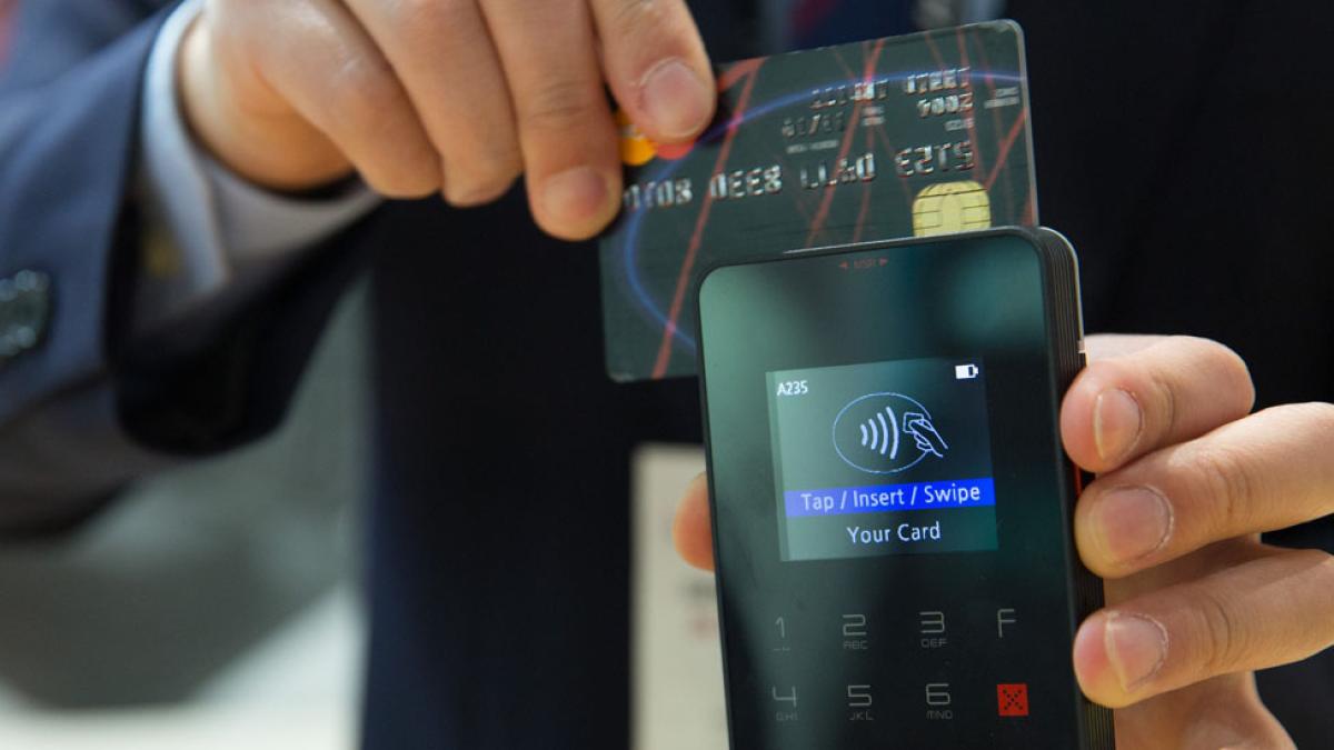 man in business suit swiping a credit card at a payment machine