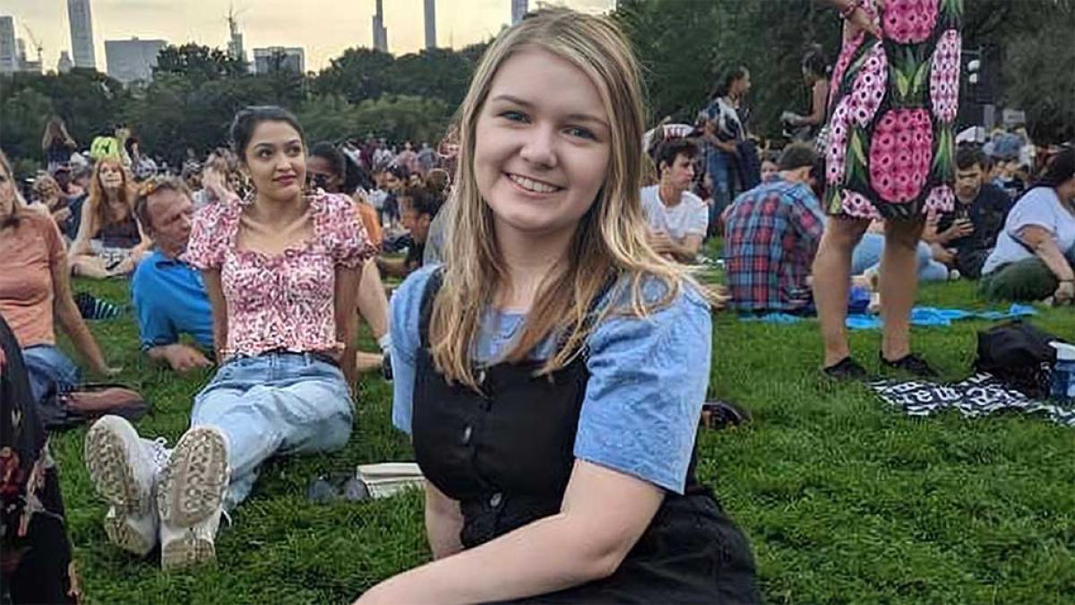 blonde girl sitting on the lawn in a crowd