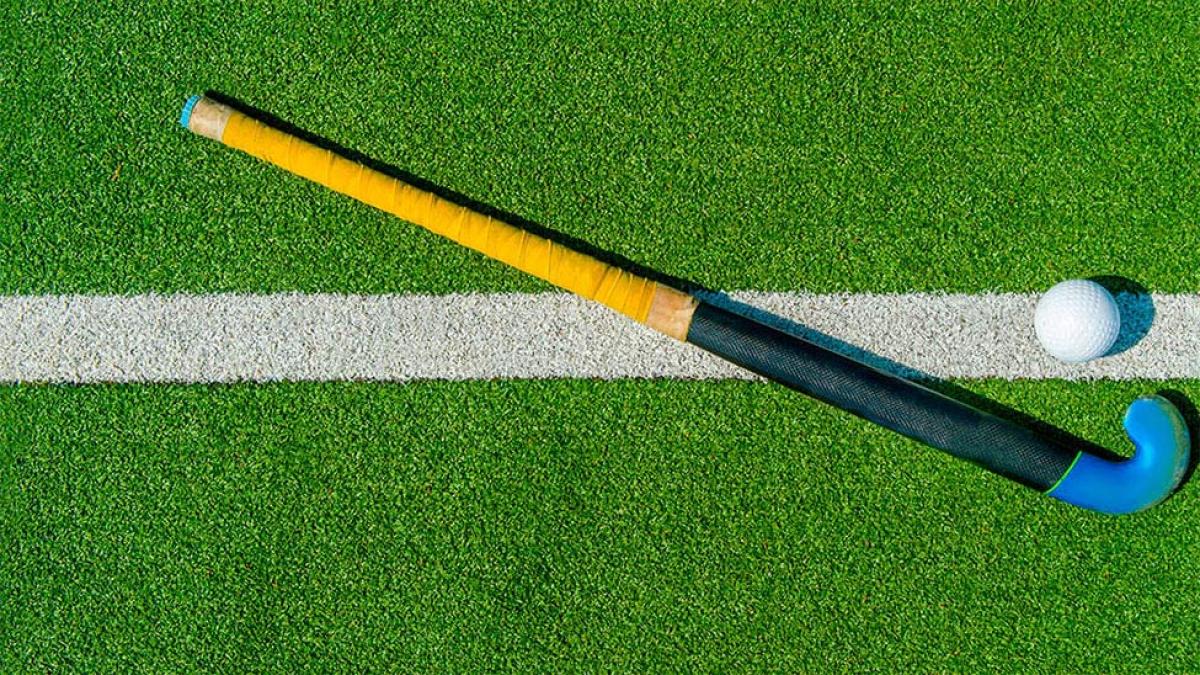 field hockey stick and ball laying on a turf field