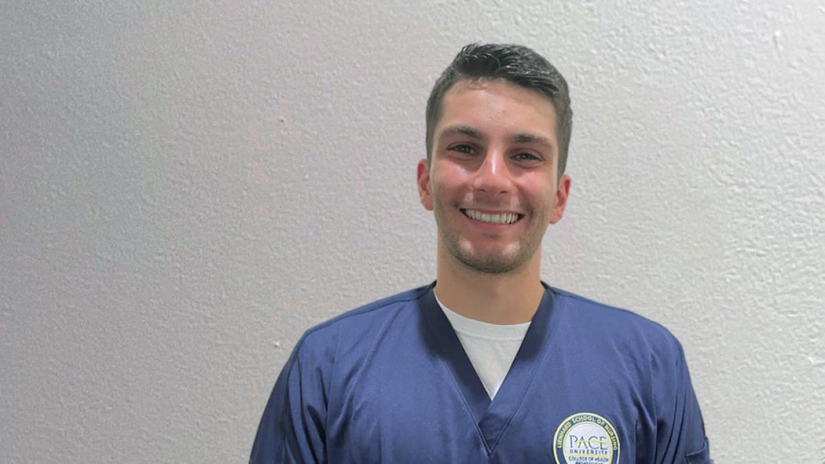 young man in navy scrubs against a light background