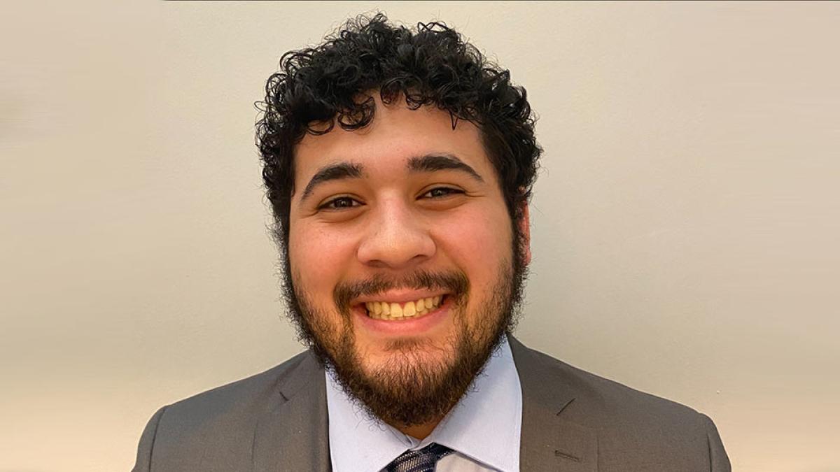 person smiling for camera in front of beige wall