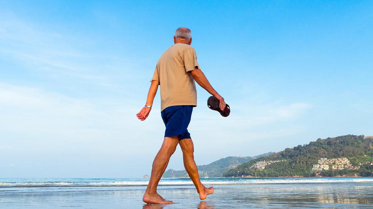 older man walking on a beach