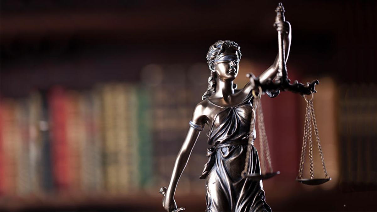 Small statue of lady justice next to a bookshelf