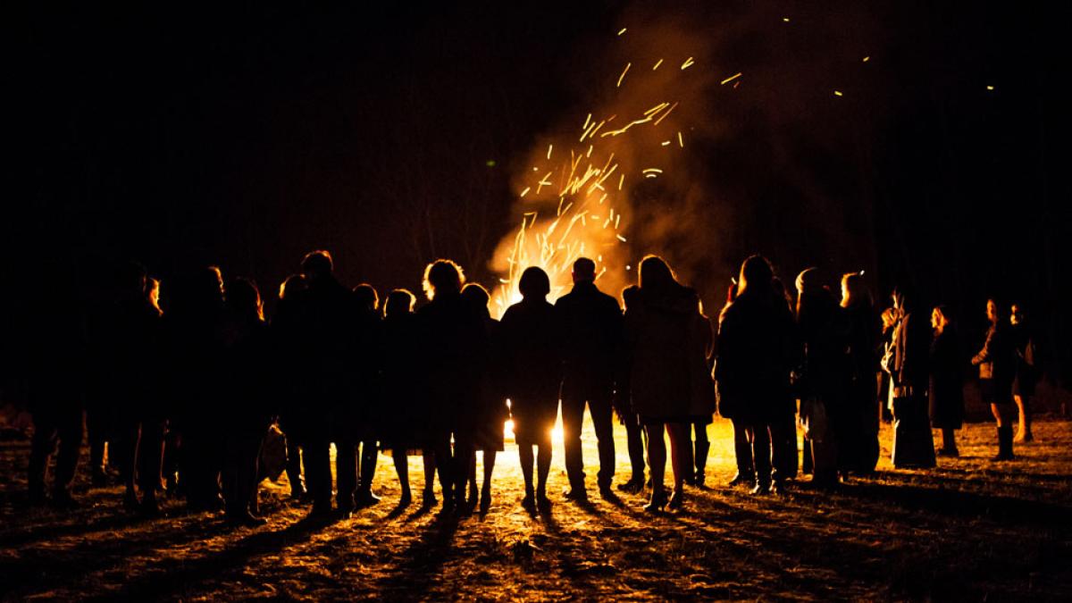 people standing around a bonfire at night