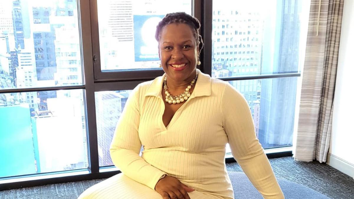 Katina Hill-Thompson wearing a white dress and posing for the camera. 