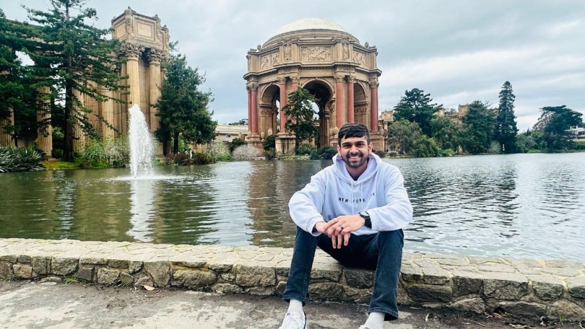 Pace student Om Gaikhe sitting in front of an old fountain and smiling for a photo.