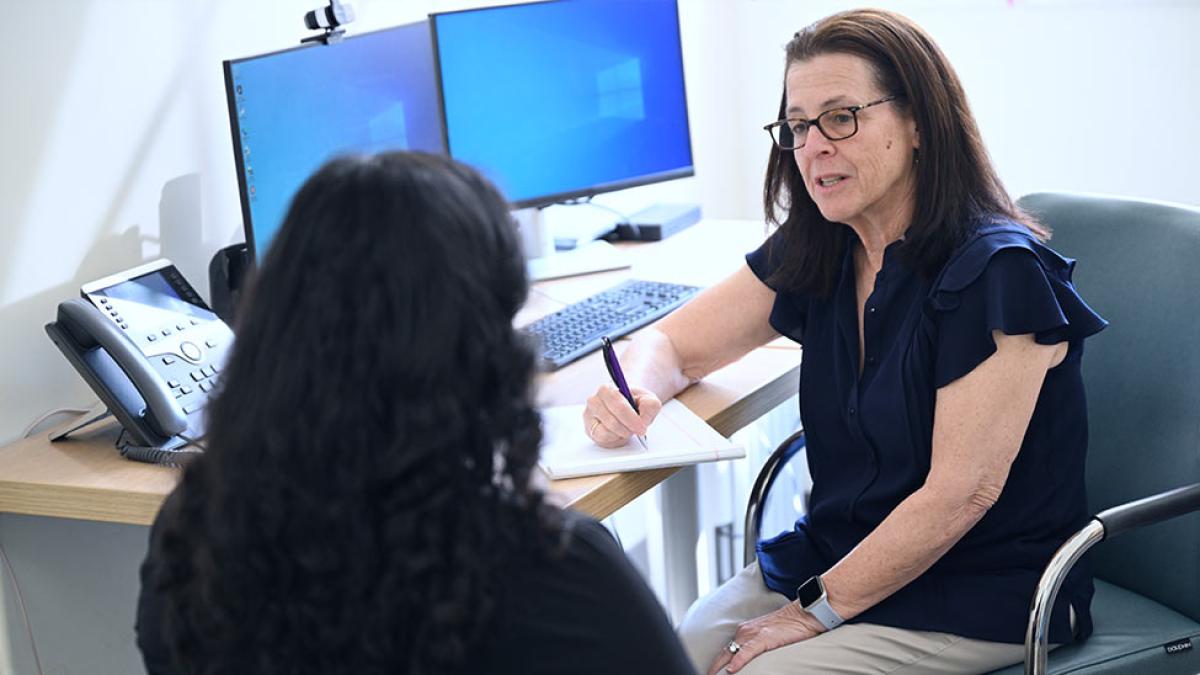 A woman in an office listening to another individual