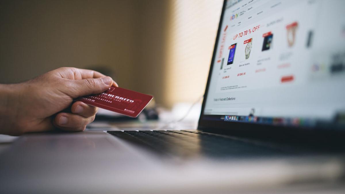 close view of ecommerce website on laptop with hand holding credit card