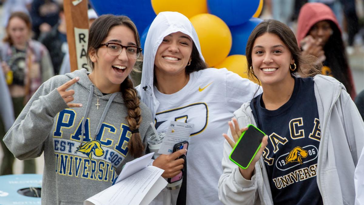 Three Pace University students smiling at the camera.