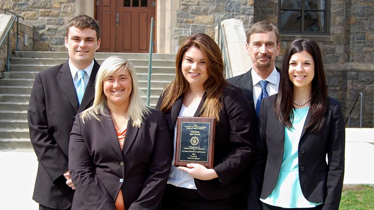 Students and professors posing for a photo with an award plaque on the Elisabeth Haub School of Law campus