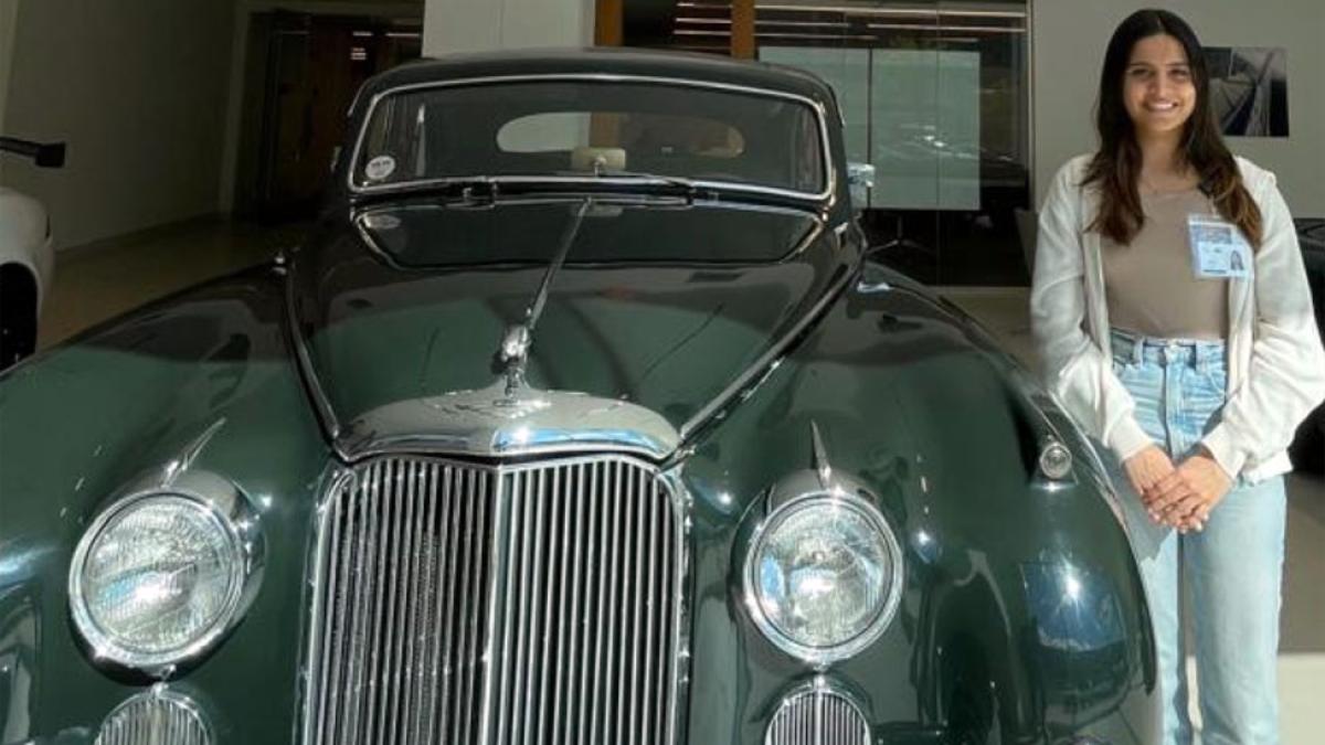 Pace University Lubin School of Business graduate student Cianna Bar '25 standing next to a vintage Jaguar automobile at her internship with Jaguar Land Rover