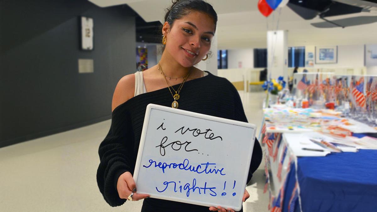 A female Pace University student holding a sign that says I vote for reproductive rights.