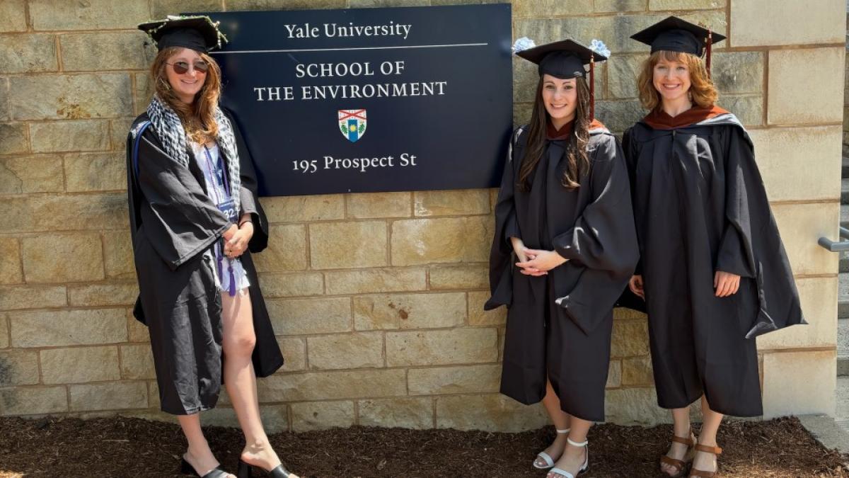 Three Elisabeth Haub School of Law joint degree students standing in front of a Yale School of the Environment sign