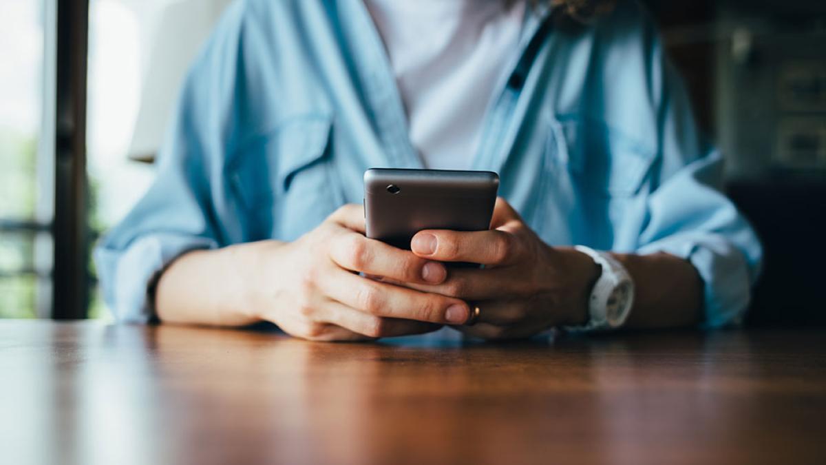 Person sitting at table with phone in their hands