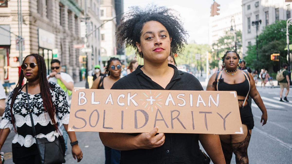 Photo by Cindy Trinh of a person of color holding a sign that says Black Asian Solidarity.