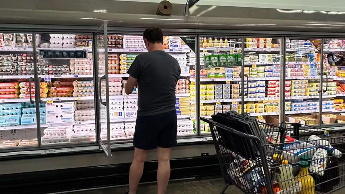 A man standing at the refrigerated shelves of a grocery store with a cart full of goods.  AP Photo/Nam Y. Huh