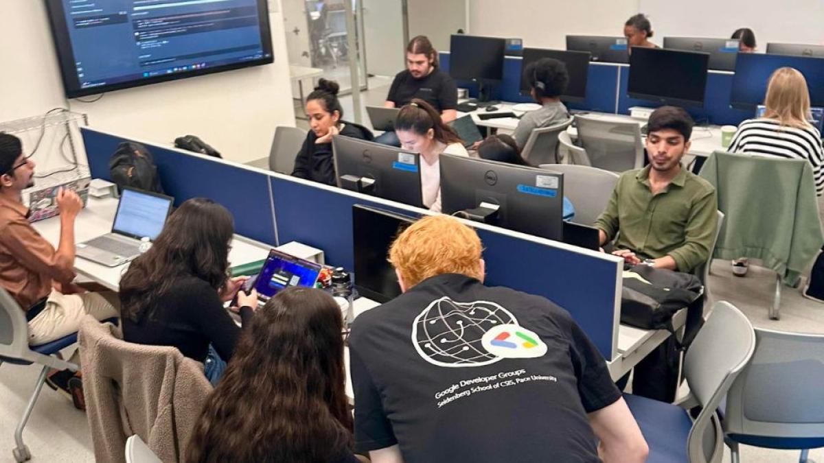 Students from the Seidenberg Google Developers Club collaborating and working on their computers in a classroom.