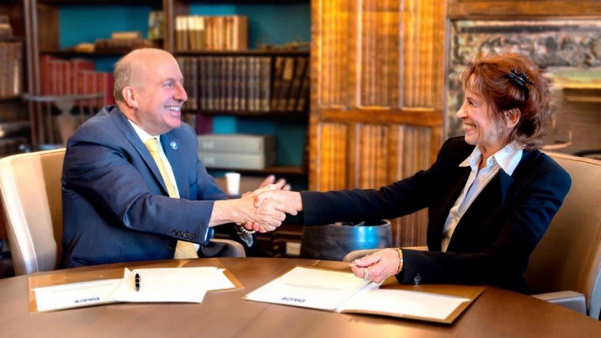 Pace University President Marvin Krislov shaking hands with Gale Epstein at a conference table.