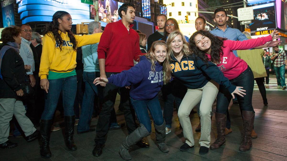 Group of Pace University New York City Campus students wearing Pace shirts and posing in Times Square