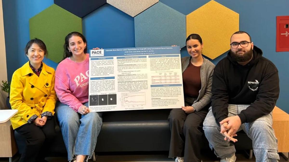 Pace University Professor Juan Shan with students and their research poster.