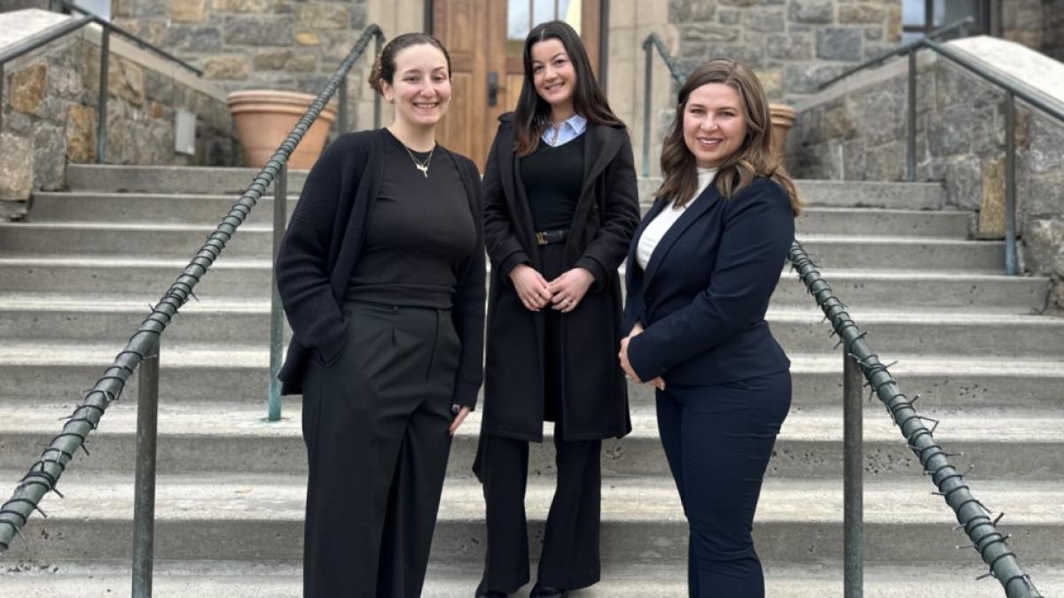 Three Elisabeth Haub School of Law at Pace University students stand on the steps outside Preston Hall