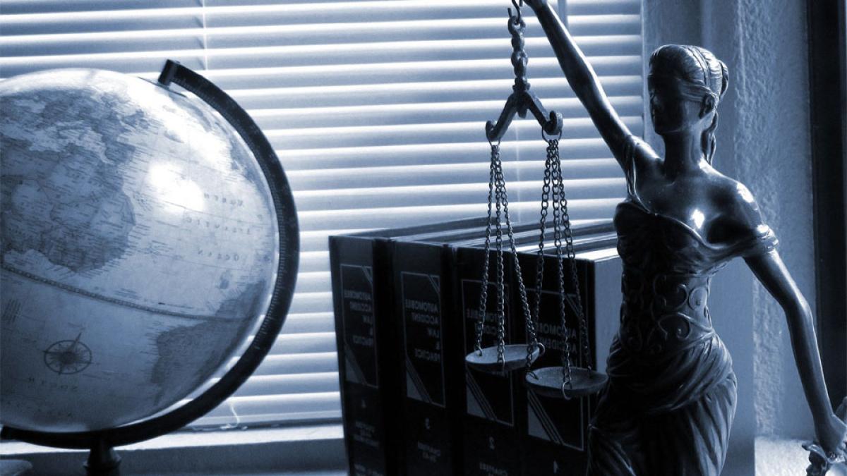 globe and statue of Lady Justice holding scales and wearing blindfold representing the legal field