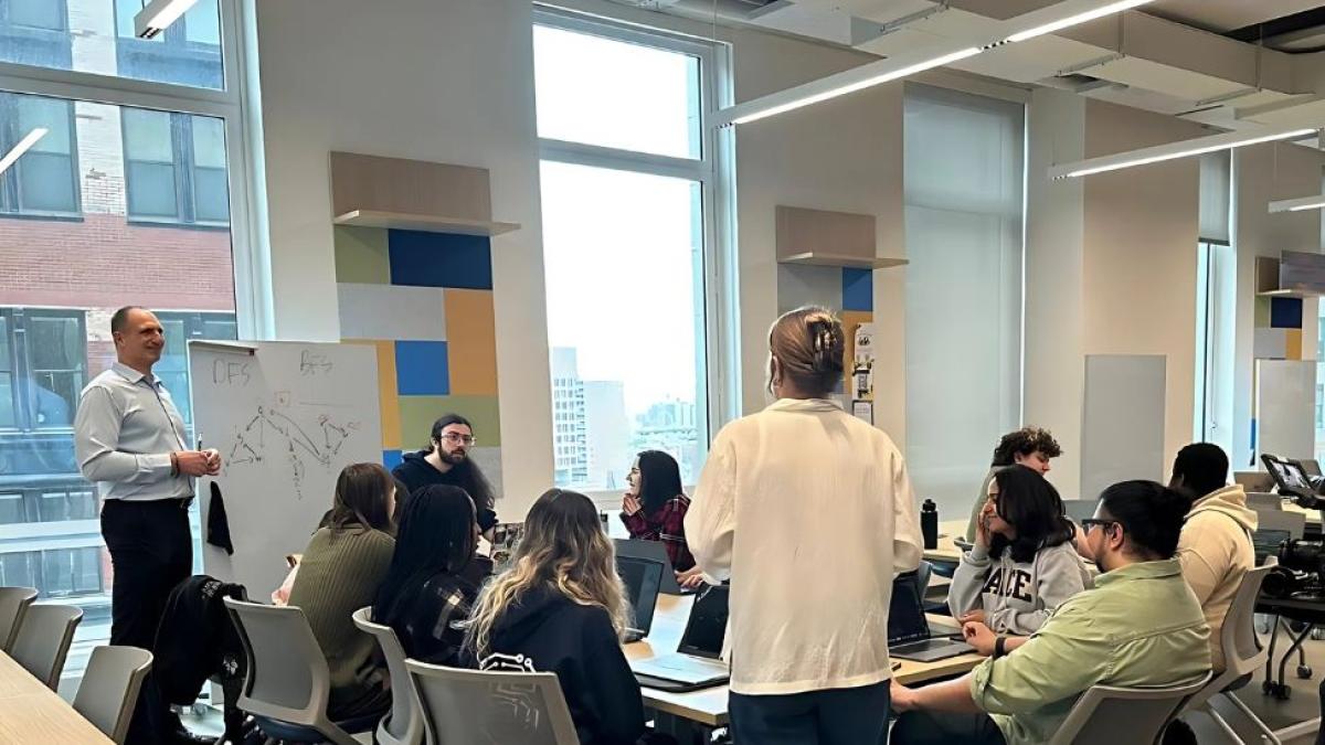 Pace Seidenberg professor Joe Acampora working with a group of students who are sitting around a table in Seidenberg's Design Factory space.