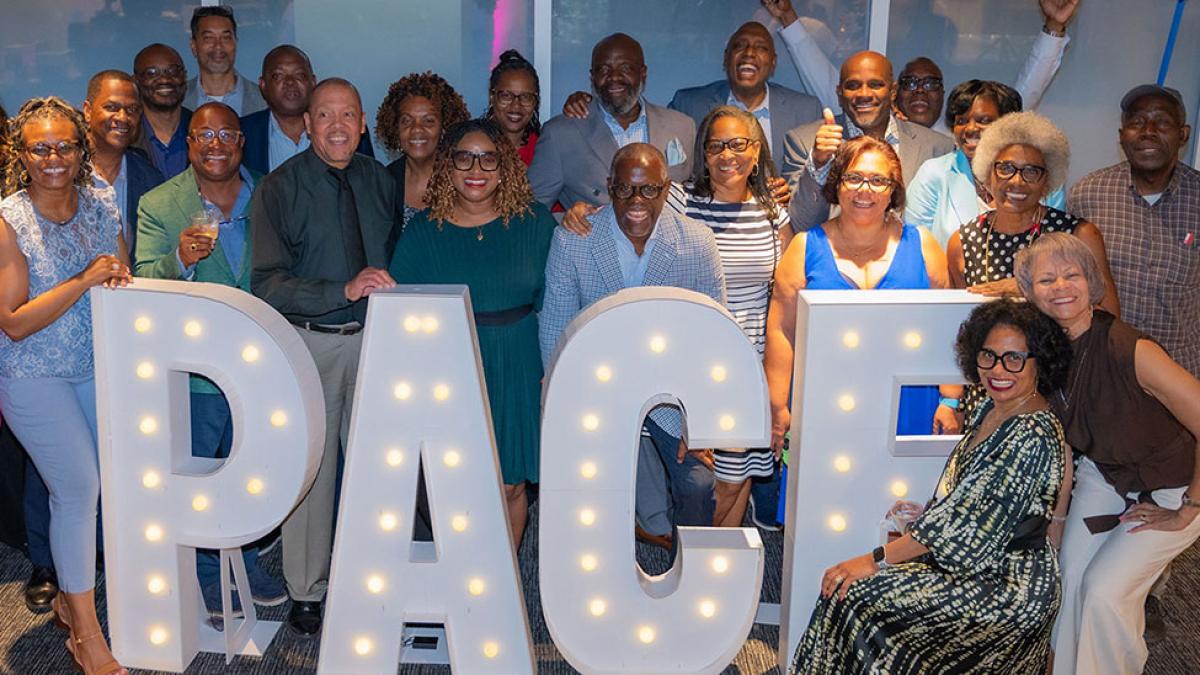 Group of Pace University standing behind a Pace sign at the 2025 Reunion.