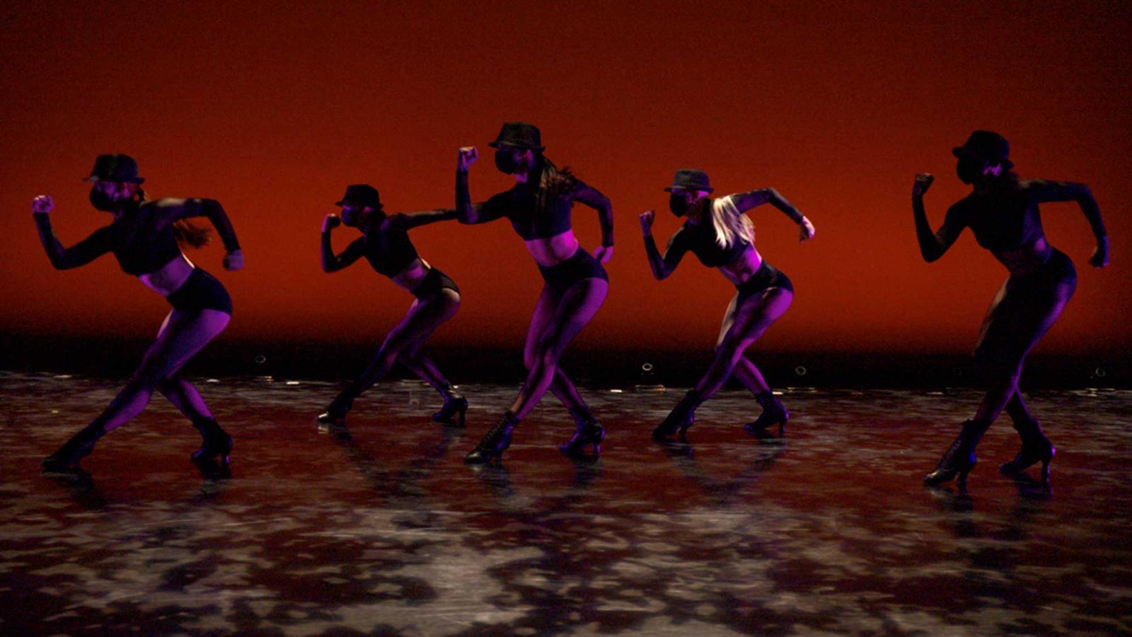 five dancers in masks on a stage