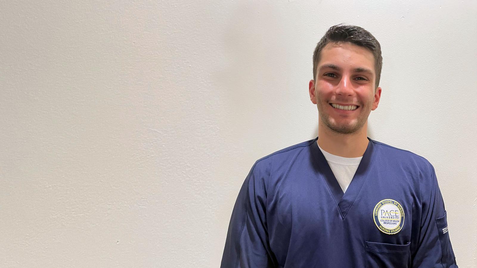 young man in navy scrubs against a light background