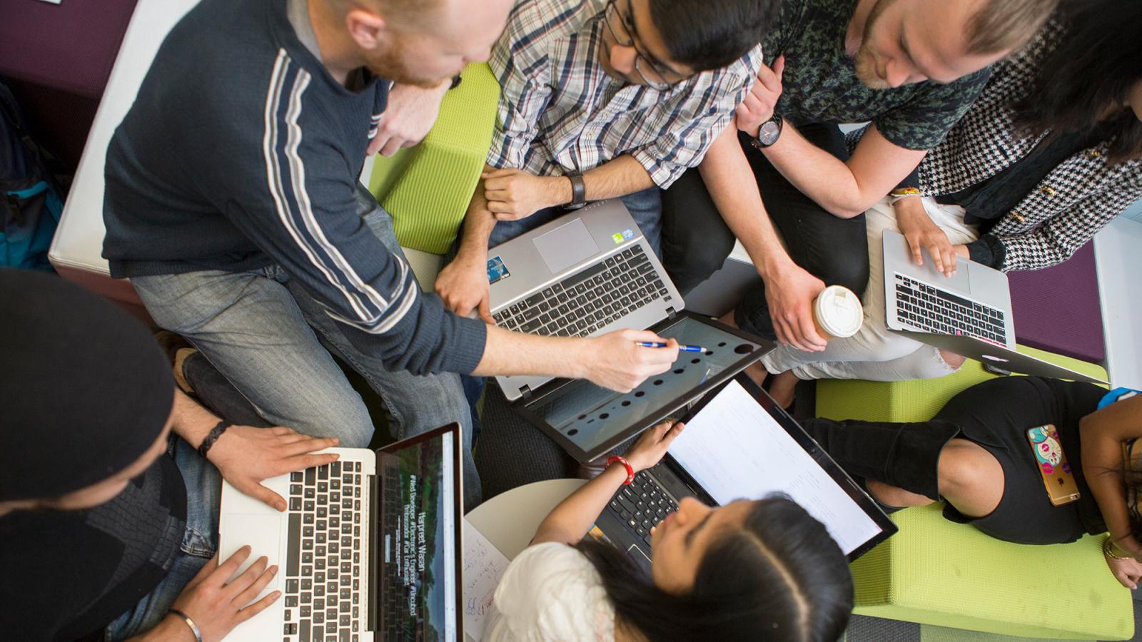 Group of students collaborating, working on their computers.