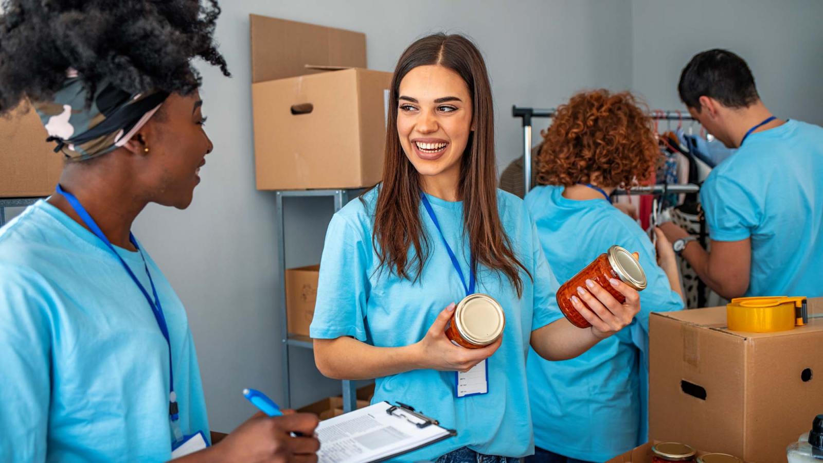 two smiling volunteers sort through pantry goods at a food bank